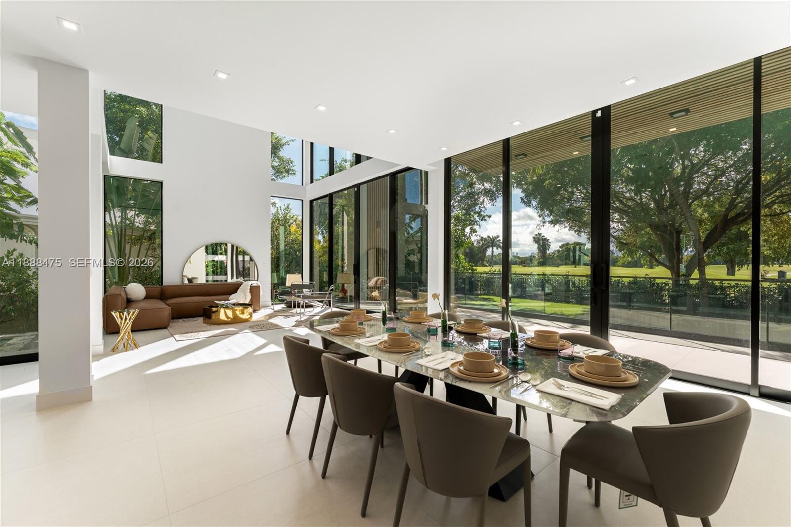 A modern dining room with floor-to-ceiling windows overlooking a golf course and green space — 3114 Prairie Ave, Miami Beach FL 33140, MIAMI BEACH, FL