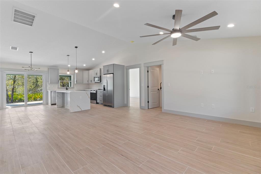 An open-concept kitchen and living area features light wood-look tile flooring and gray cabinetry — 4117 JOSEPH STREET, PORT CHARLOTTE, FL