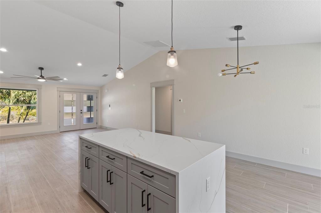 A kitchen island with gray cabinets and a white marble countertop sits in an open room — 4117 JOSEPH STREET, PORT CHARLOTTE, FL