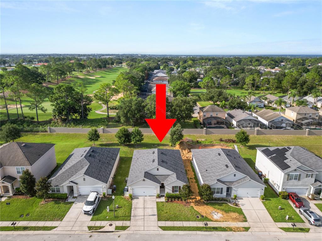 An aerial view shows a suburban house with a red arrow pointing to its backyard — 813 SHEEN CIRCLE, HAINES CITY, FL