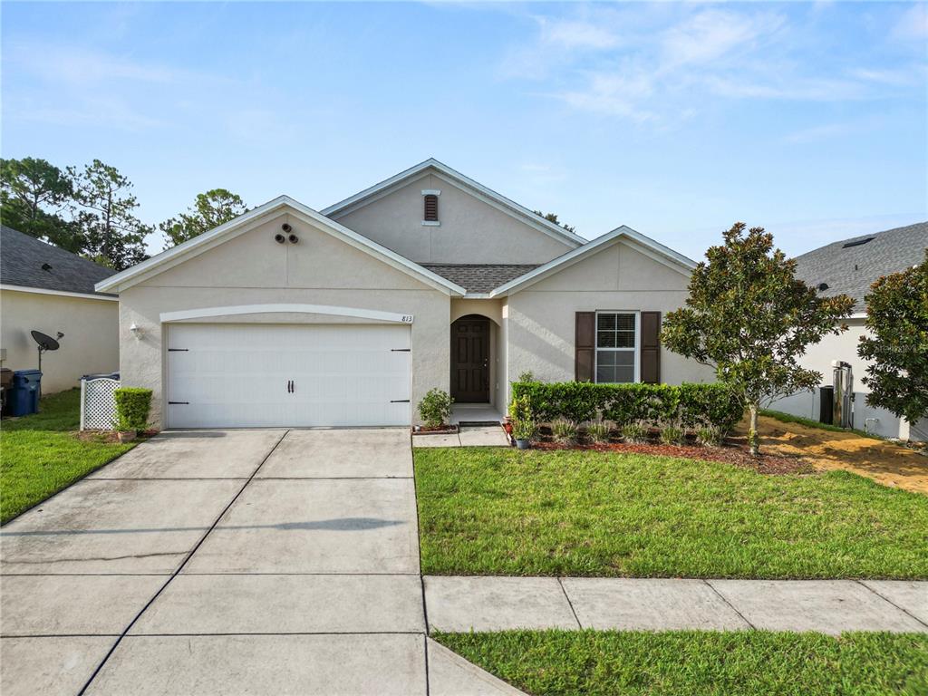 A single-story suburban house with a two-car garage, beige stucco exterior, and a front lawn — 813 SHEEN CIRCLE, HAINES CITY, FL