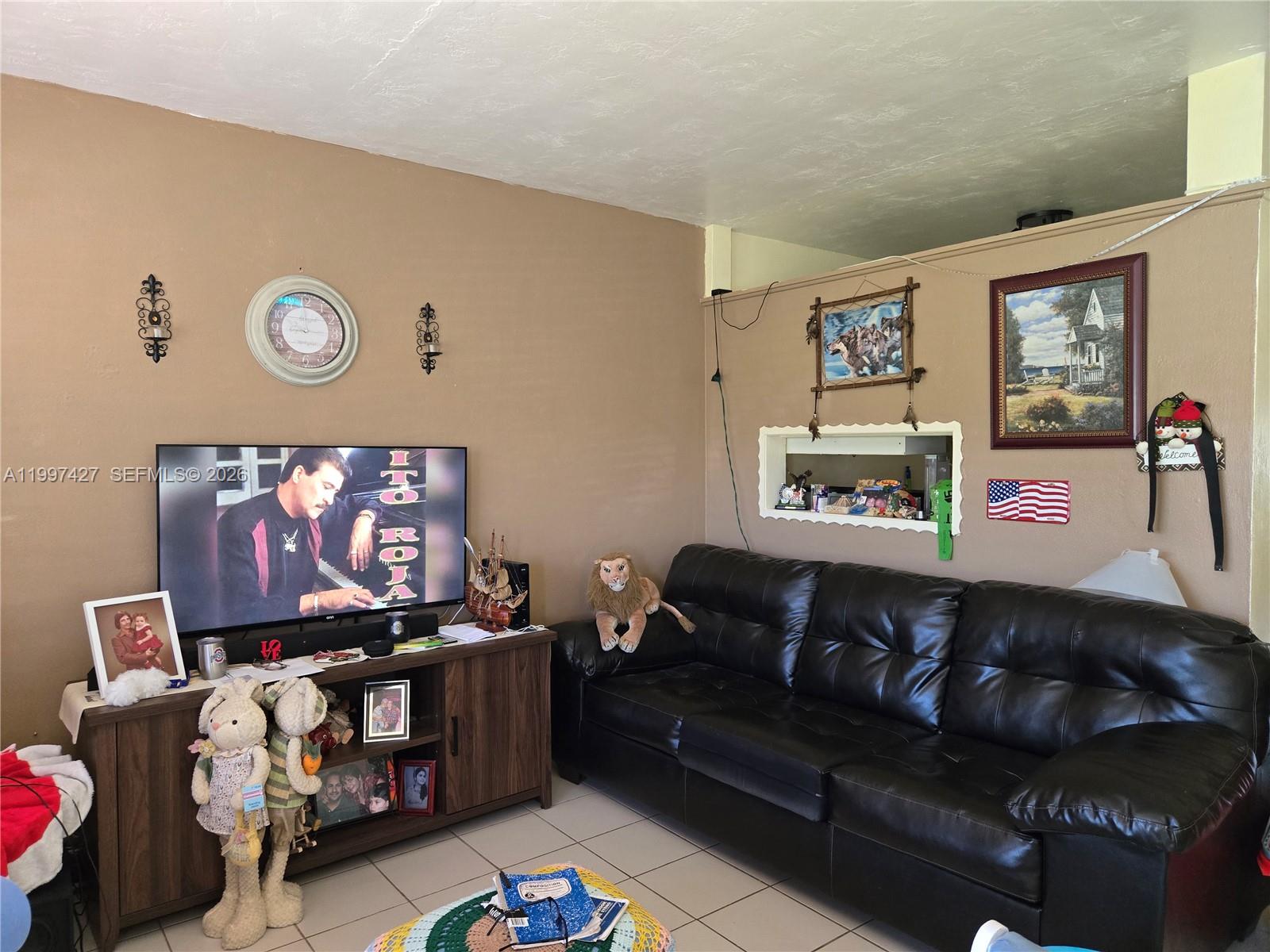 A living room features a black leather sofa, a television on a console, and tiled floors — 820 SW 11th Ave # 5B, Hallandale Beach FL 33009, HALLANDALE BEACH, FL