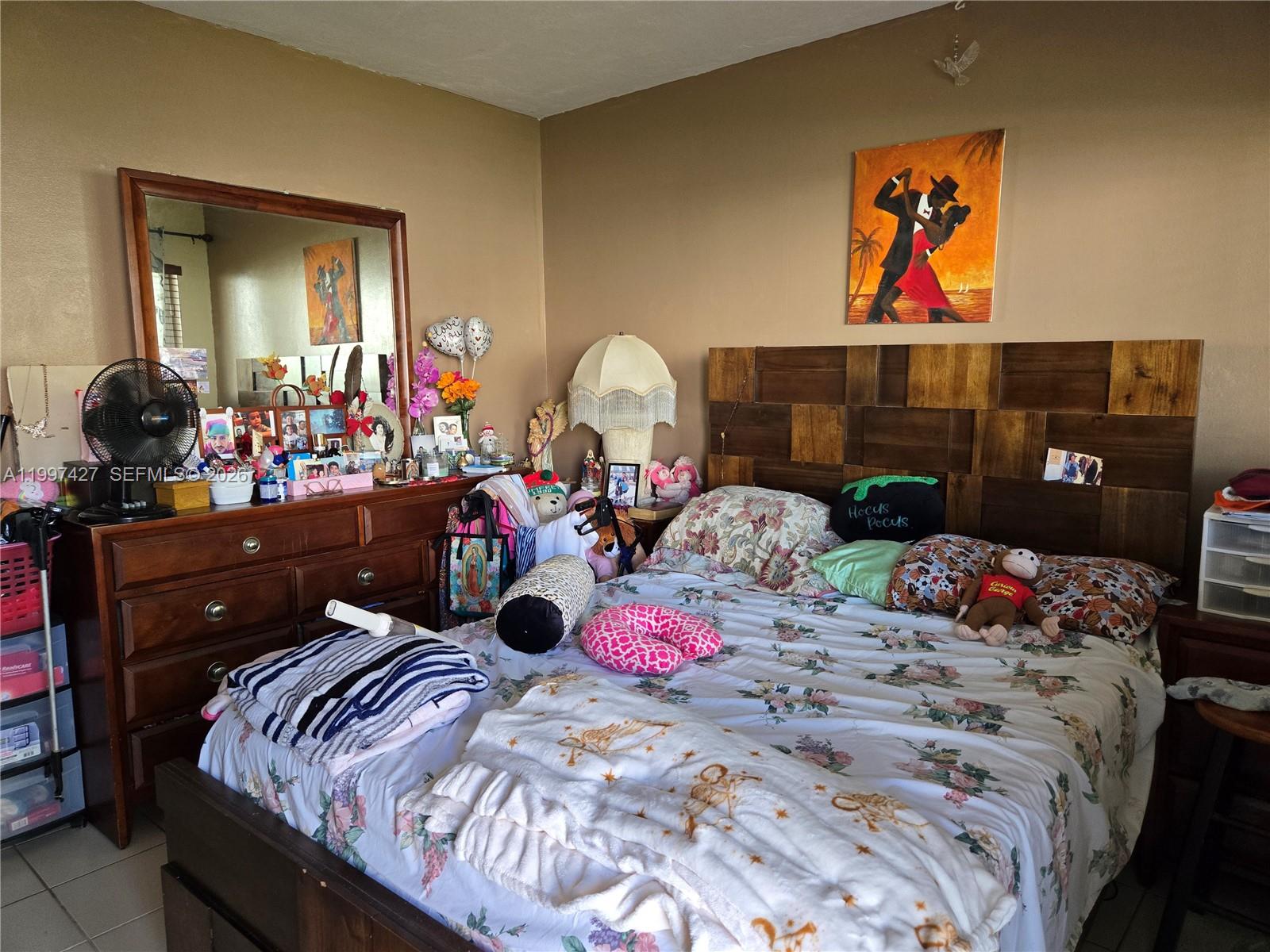 A bedroom features a wooden headboard, floral bedding, a dresser with a mirror, and wall art — 820 SW 11th Ave # 5B, Hallandale Beach FL 33009, HALLANDALE BEACH, FL