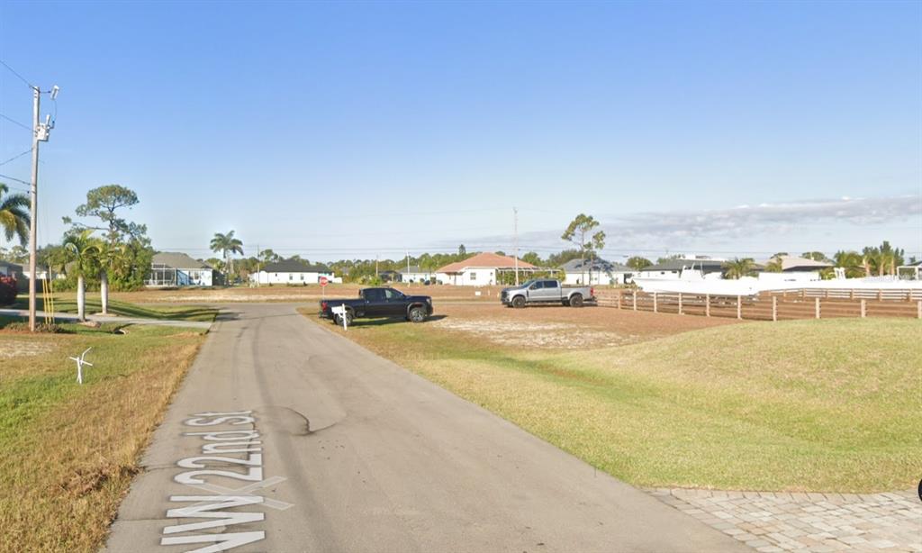 An empty residential lot with two parked trucks and a boat on a trailer — 2458 NW 22ND STREET, CAPE CORAL, FL