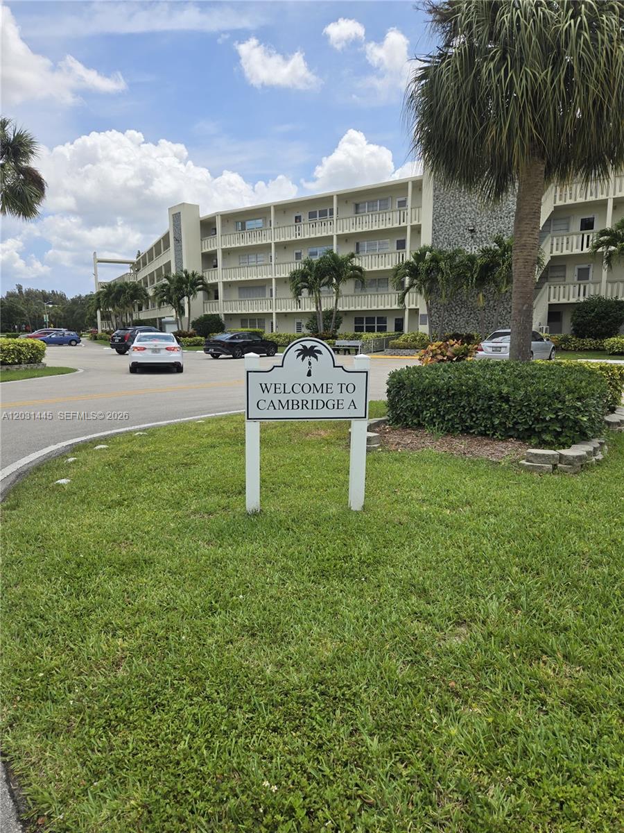 A sign reading Welcome to Cambridge A stands on a lawn before a multi-story building — DEERFIELD BEACH, FL