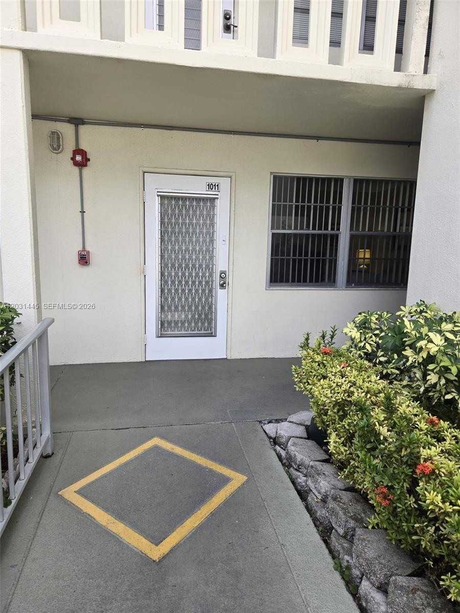 The exterior view shows a white door labeled 1011, a window with security bars, and landscaping — DEERFIELD BEACH, FL