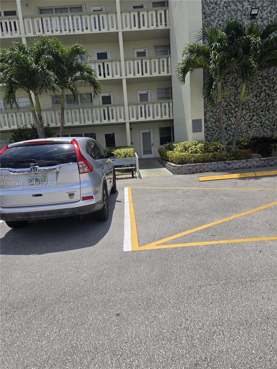 A silver SUV is parked in a lot next to a multi-story apartment building — DEERFIELD BEACH, FL