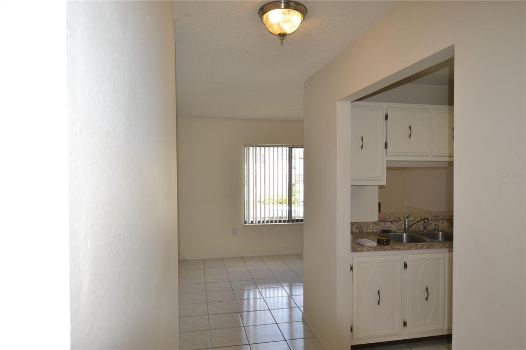 A view from a hallway looking into a tiled dining area and a small kitchen — 329 MOORINGS COVE DRIVE, TARPON SPRINGS, FL