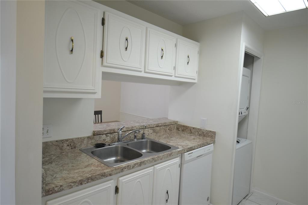 A kitchen features white cabinets, a double-basin sink, laminate countertops, and an adjacent laundry closet — 329 MOORINGS COVE DRIVE, TARPON SPRINGS, FL