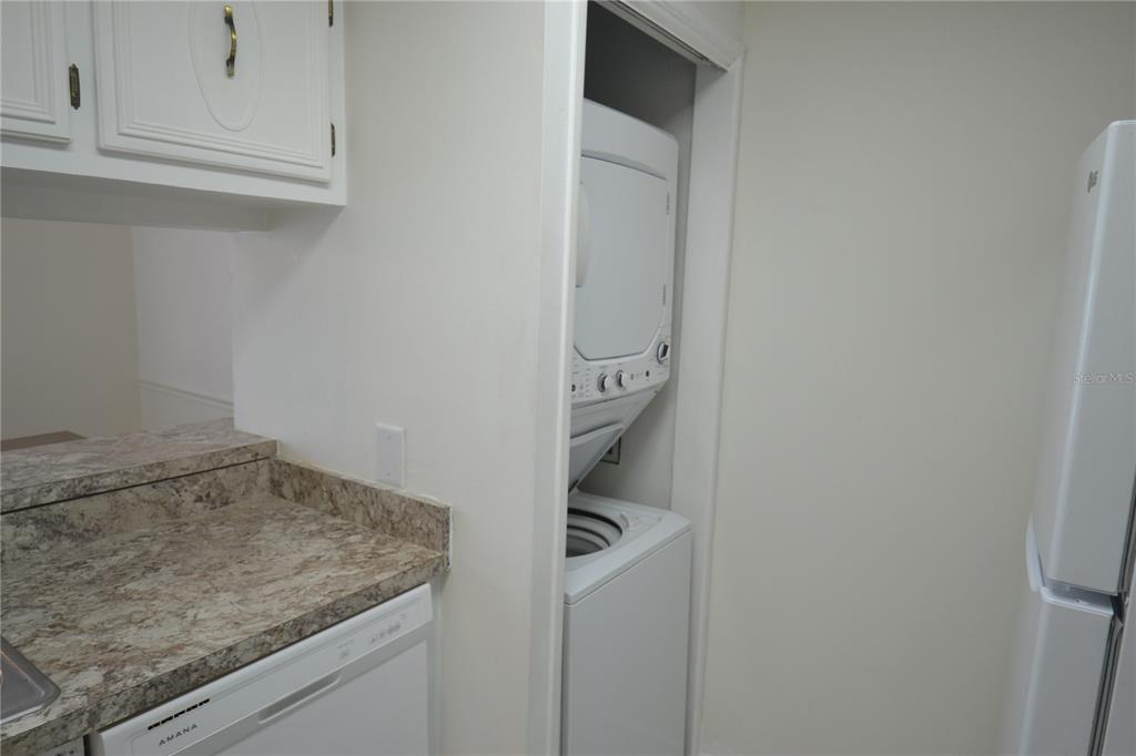 A kitchen area features a white stacked washer and dryer unit next to a refrigerator — 329 MOORINGS COVE DRIVE, TARPON SPRINGS, FL