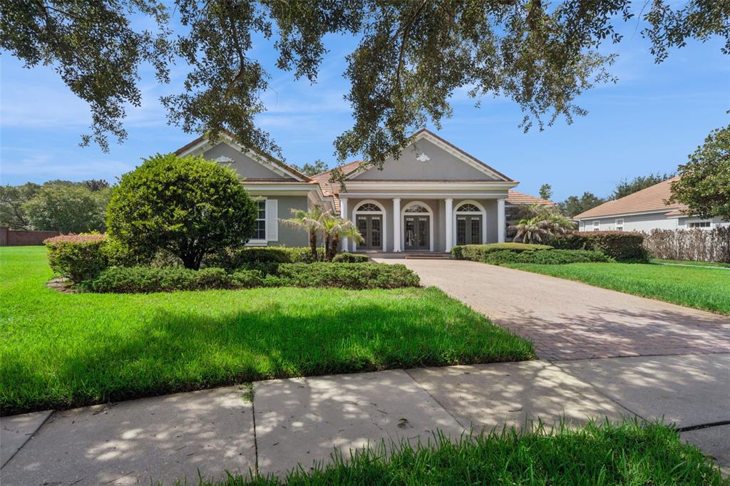 A single-story house with a paved driveway, columns, and a large front lawn — 6533 CARTMEL LN, WINDERMERE, FL