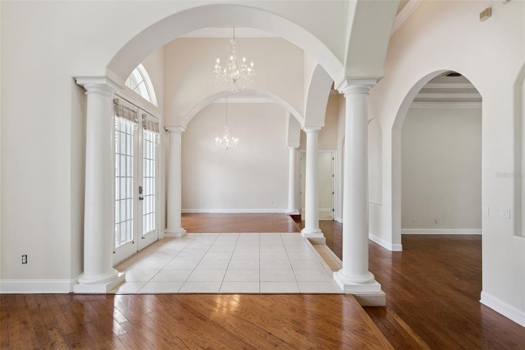 An entryway with tile flooring, white columns, arched openings, and two crystal chandeliers — 6533 CARTMEL LN, WINDERMERE, FL