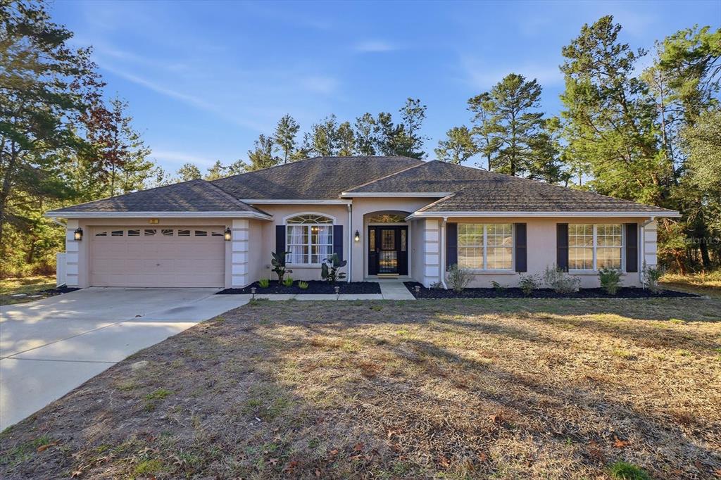 A single-story house with a beige stucco exterior, a two-car garage, and a front yard — 21 LOBELIA COURT, HOMOSASSA, FL