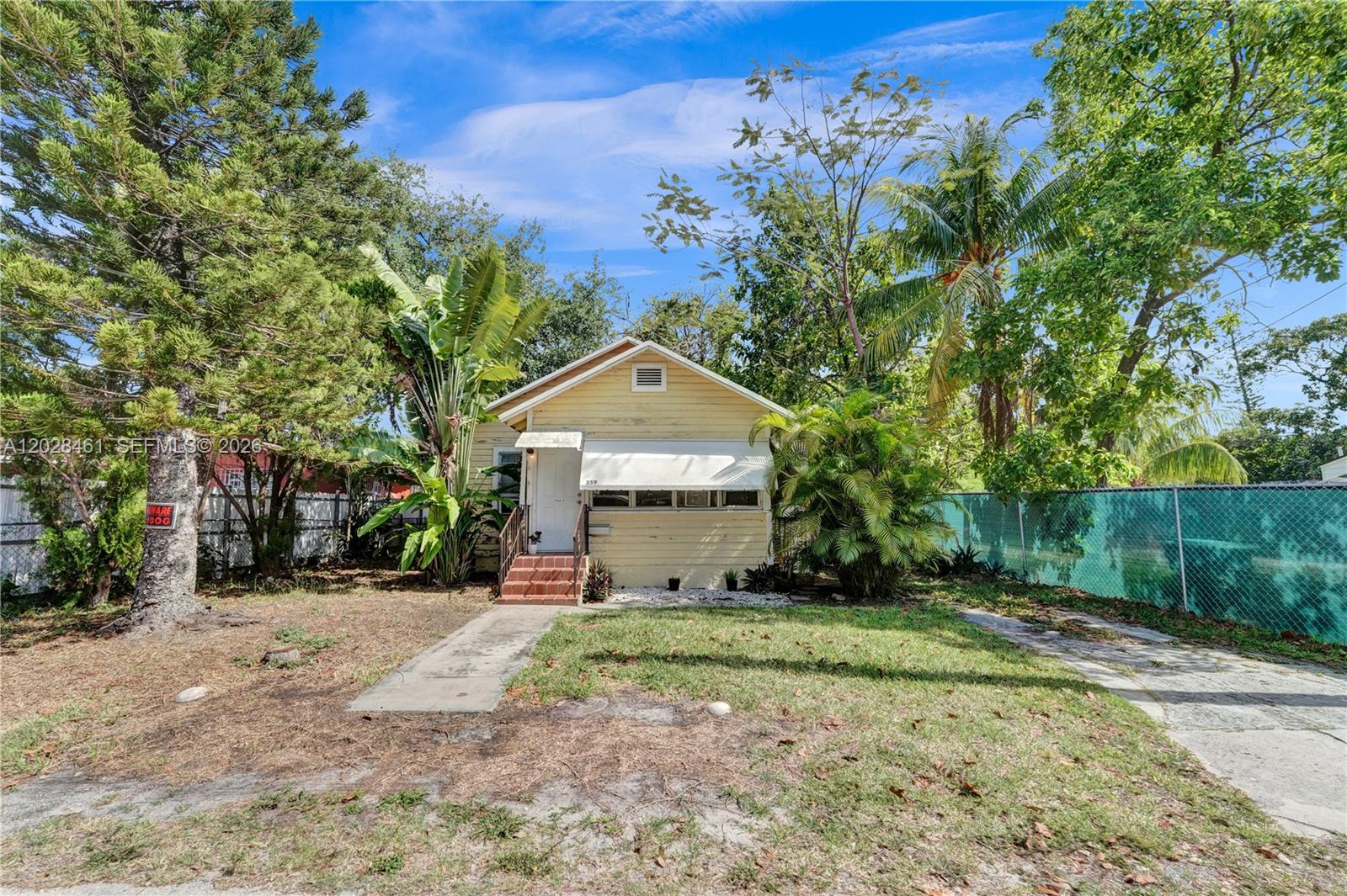 A small, yellow, single-story house with a front porch and a chain-link fence — 259 NE 57th St, Miami FL 33137, MIAMI, FL
