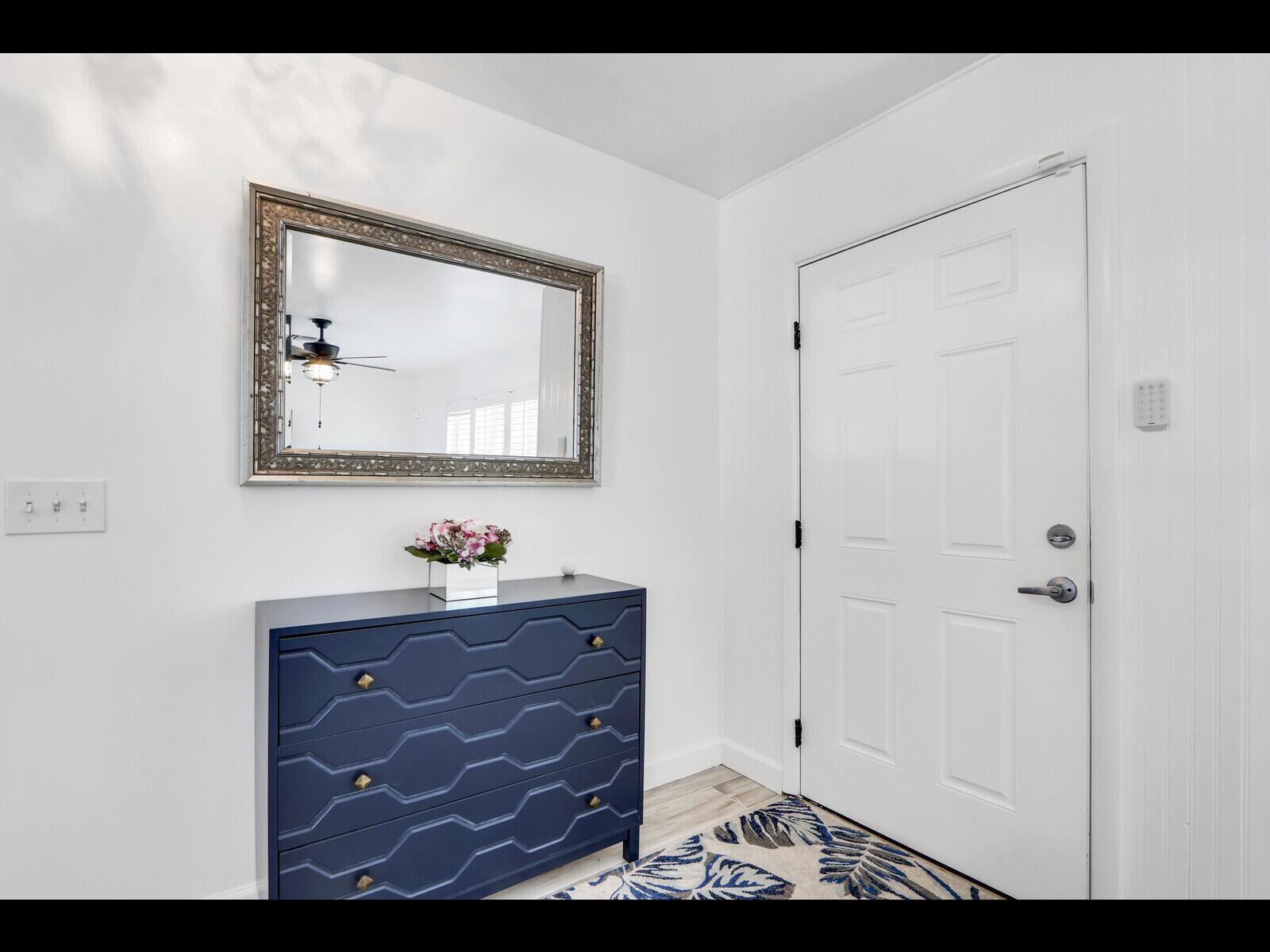 An entryway features a navy blue dresser, a decorative mirror, and a white door — 609 Oak Terrace, Jupiter FL 33458, JUPITER, FL