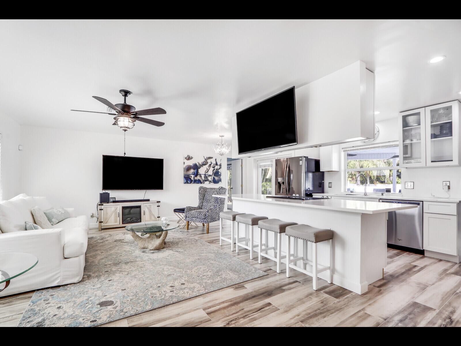 An open-concept living room and kitchen featuring white cabinetry, a breakfast bar, and wood-look flooring — 609 Oak Terrace, Jupiter FL 33458, JUPITER, FL