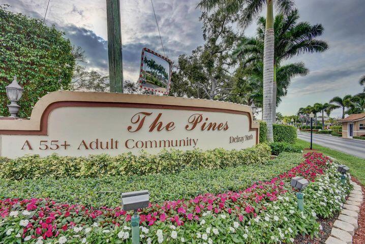 A sign for The Pines 55+ Adult Community stands in front of a landscaped garden — 1740 NW 19th Terrace # 202, Delray Beach FL 33445, DELRAY BEACH, FL