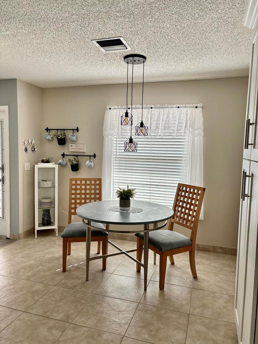 A dining area features a round table, two wooden chairs, and a hanging pendant light — 1740 NW 19th Terrace # 202, Delray Beach FL 33445, DELRAY BEACH, FL