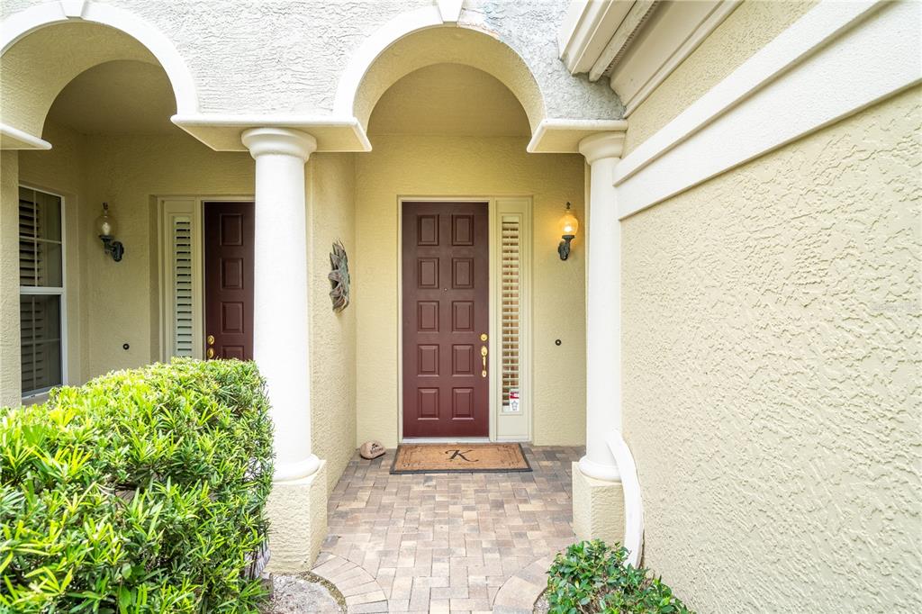 A front entryway features a brown door, white columns, and a paved walkway — 5204 BOUCHARD CIRCLE UNIT 102, SARASOTA, FL