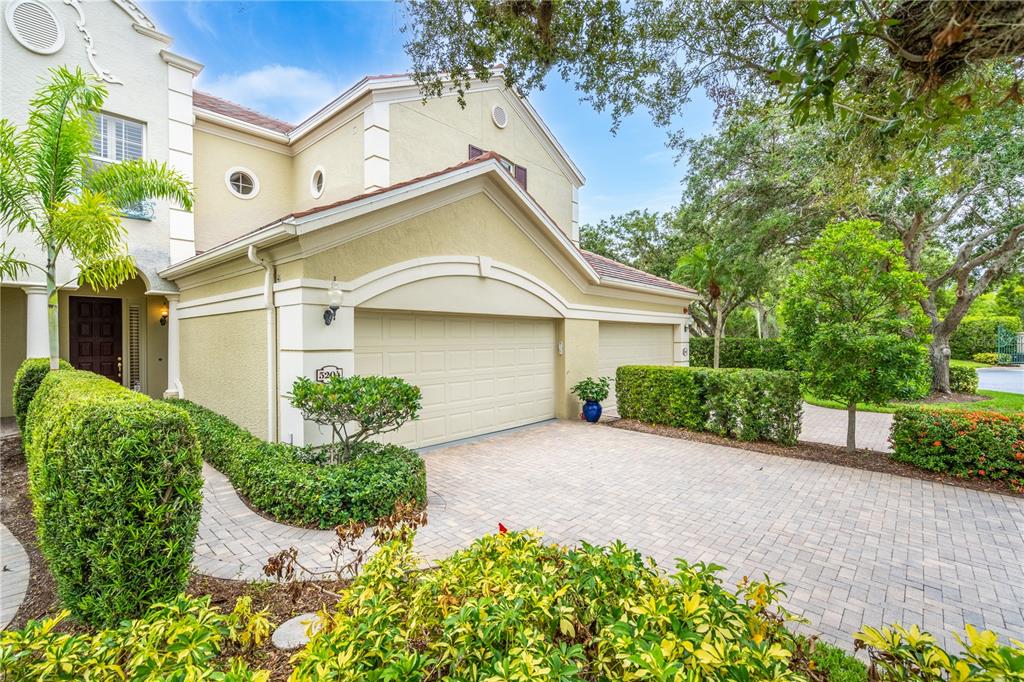 A two-story house with a beige stucco exterior, a paved driveway, and a two-car garage — 5204 BOUCHARD CIRCLE UNIT 102, SARASOTA, FL