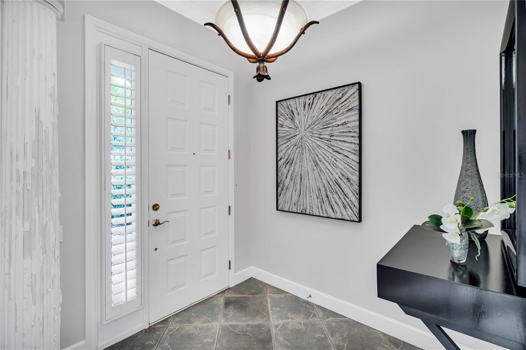 An entryway features a white door, a dark console table, and a modern ceiling light — 5204 BOUCHARD CIRCLE UNIT 102, SARASOTA, FL