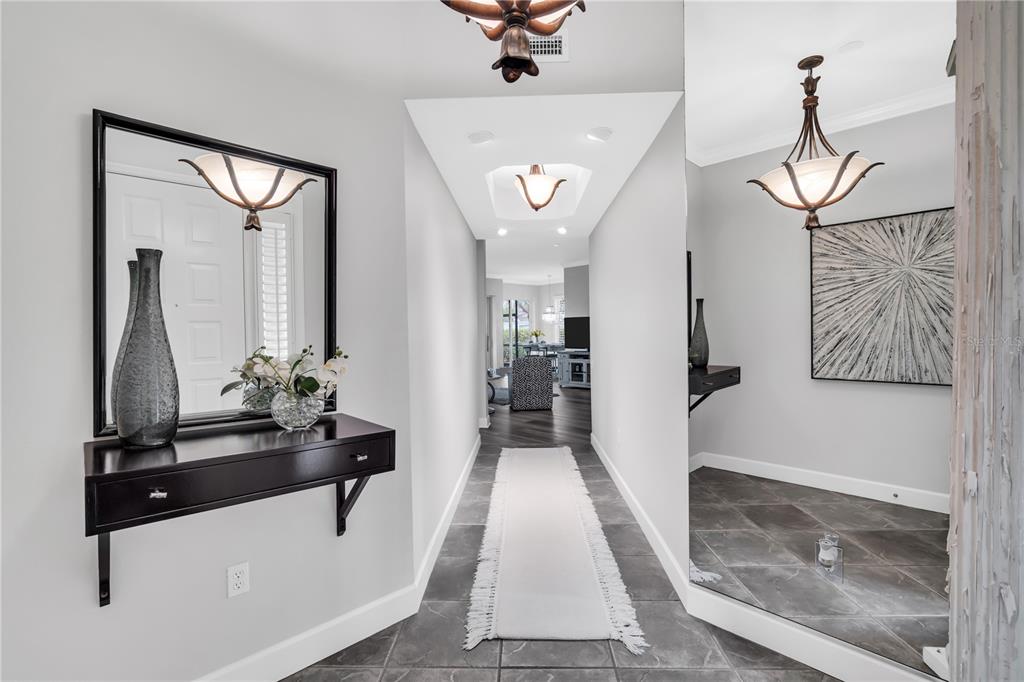 A tiled entryway features a floating console table, a large mirror, and a central hallway — 5204 BOUCHARD CIRCLE UNIT 102, SARASOTA, FL
