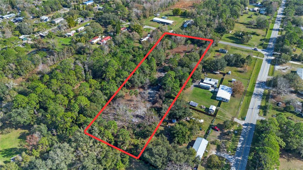 An aerial view shows a rectangular, tree-covered vacant lot outlined in red next to a road — 1520 8TH STREET, ORLANDO, FL