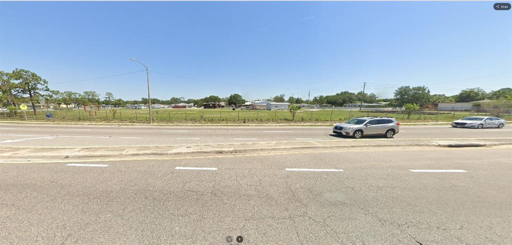 A wide, paved road runs in front of a large, grassy, fenced-in vacant lot — HWY 60 E, LAKE WALES, FL