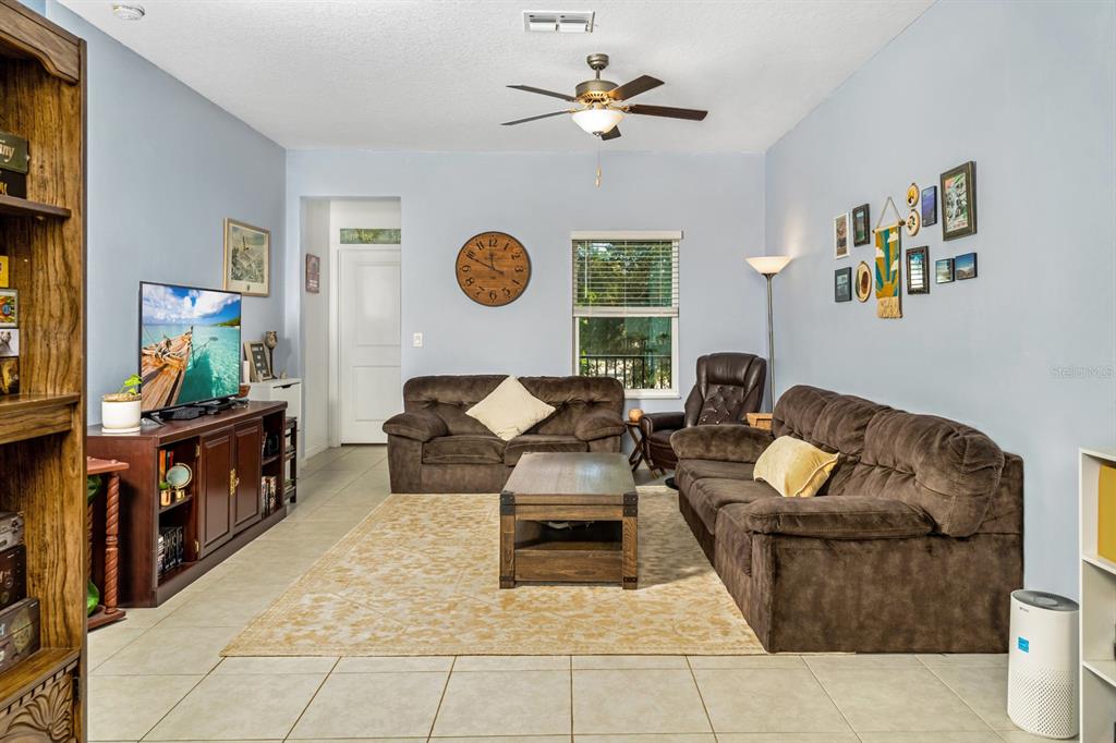 A living room features brown sofas, a wooden coffee table, and a large wall clock — 842 TENNYSON MILL CIRCLE, TAMPA, FL
