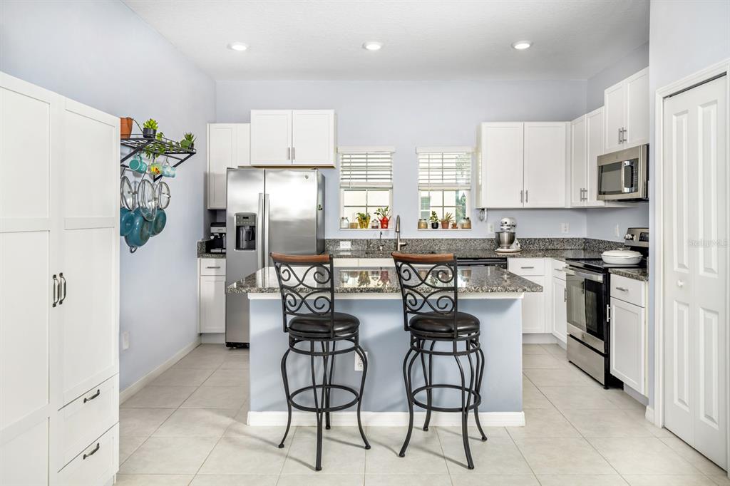 A dining area with a dark wood table and chairs opens into a white kitchen — 842 TENNYSON MILL CIRCLE, TAMPA, FL