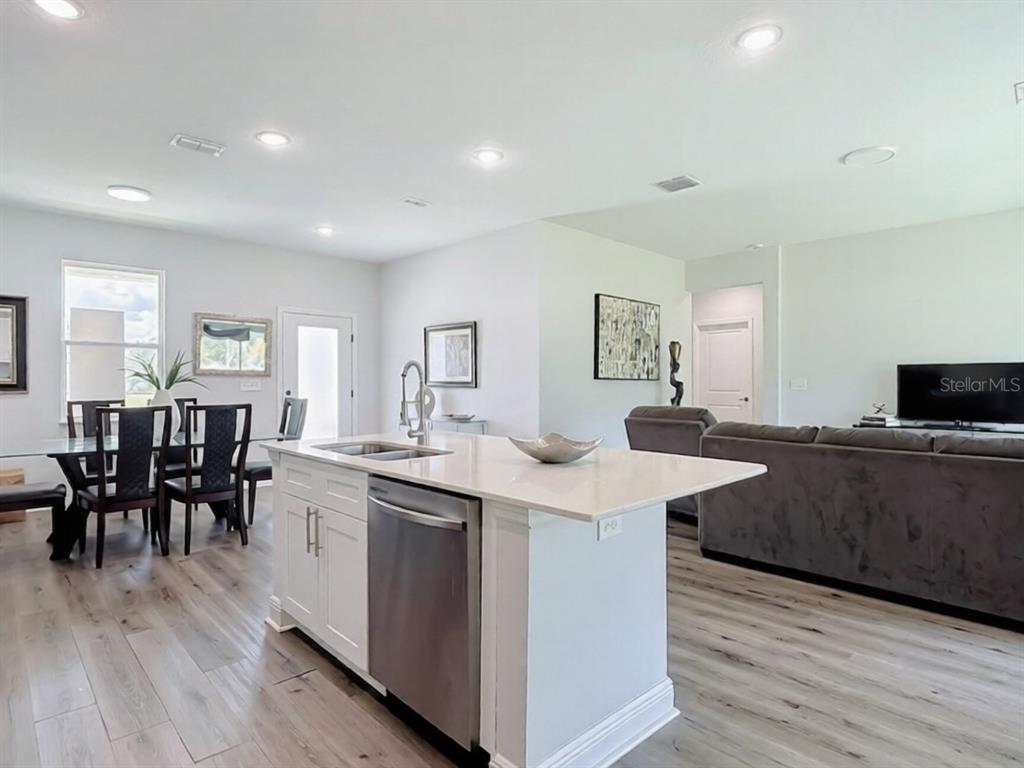 A kitchen island with a stainless steel dishwasher sits in an open-concept living area — 1101 SAINT TROPEZ COURT, KISSIMMEE, FL