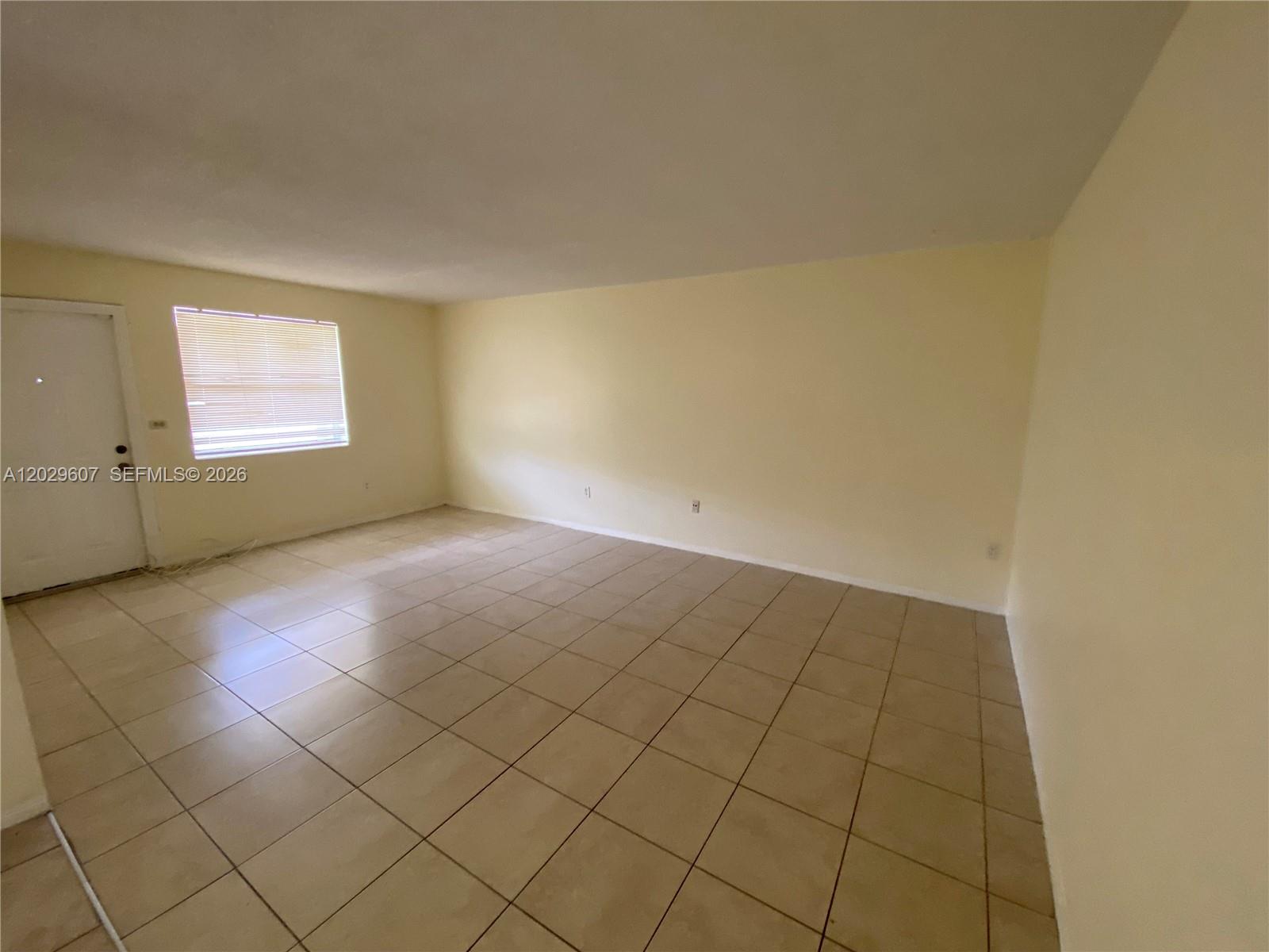 An empty room features light-colored walls, a single window with blinds, and tiled flooring — 2400 NE 188th St # 2404, Miami FL 33180, MIAMI, FL