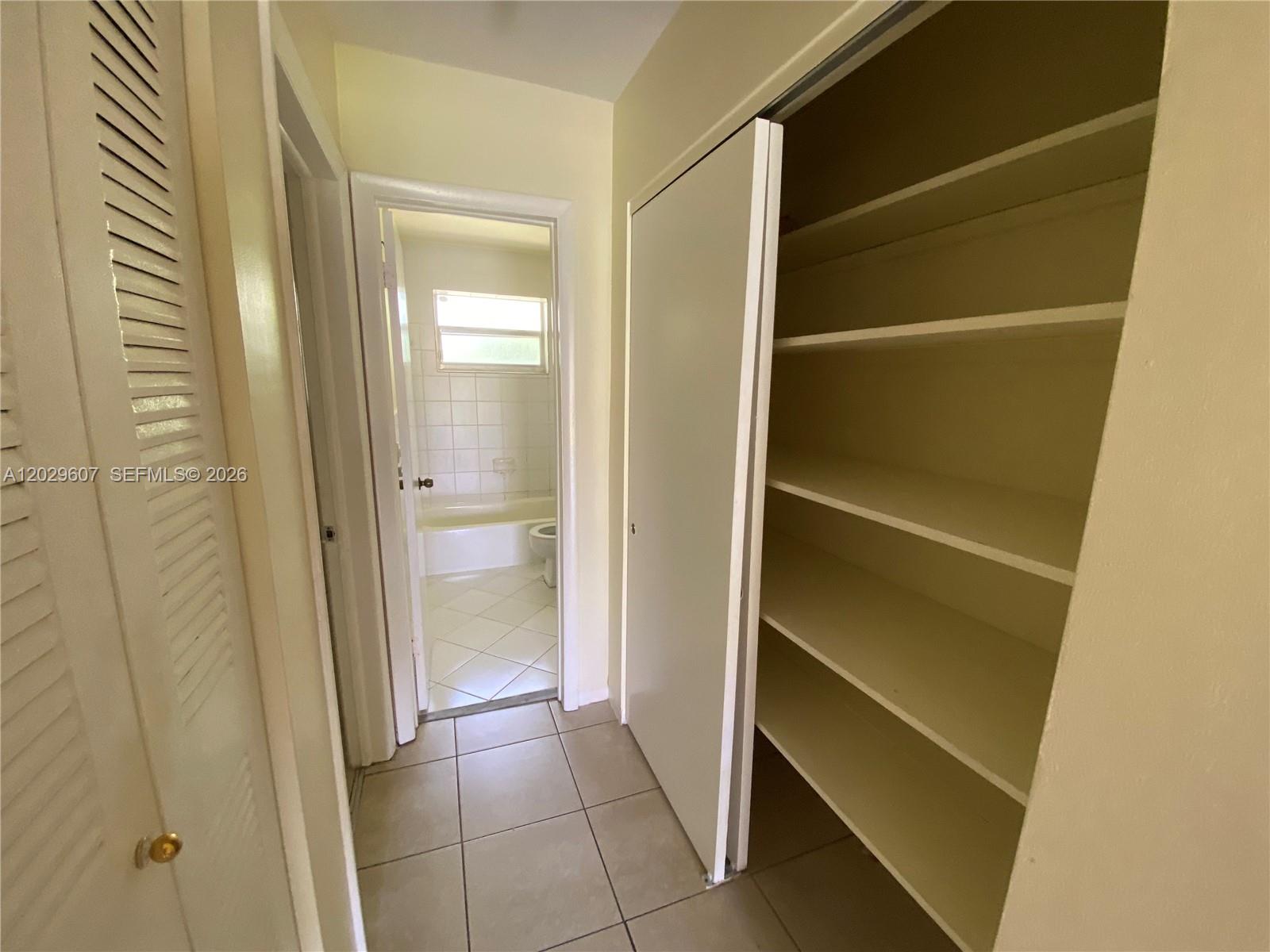 A hallway features a tiled floor, a built-in shelving unit, and a doorway to a bathroom — 2400 NE 188th St # 2404, Miami FL 33180, MIAMI, FL