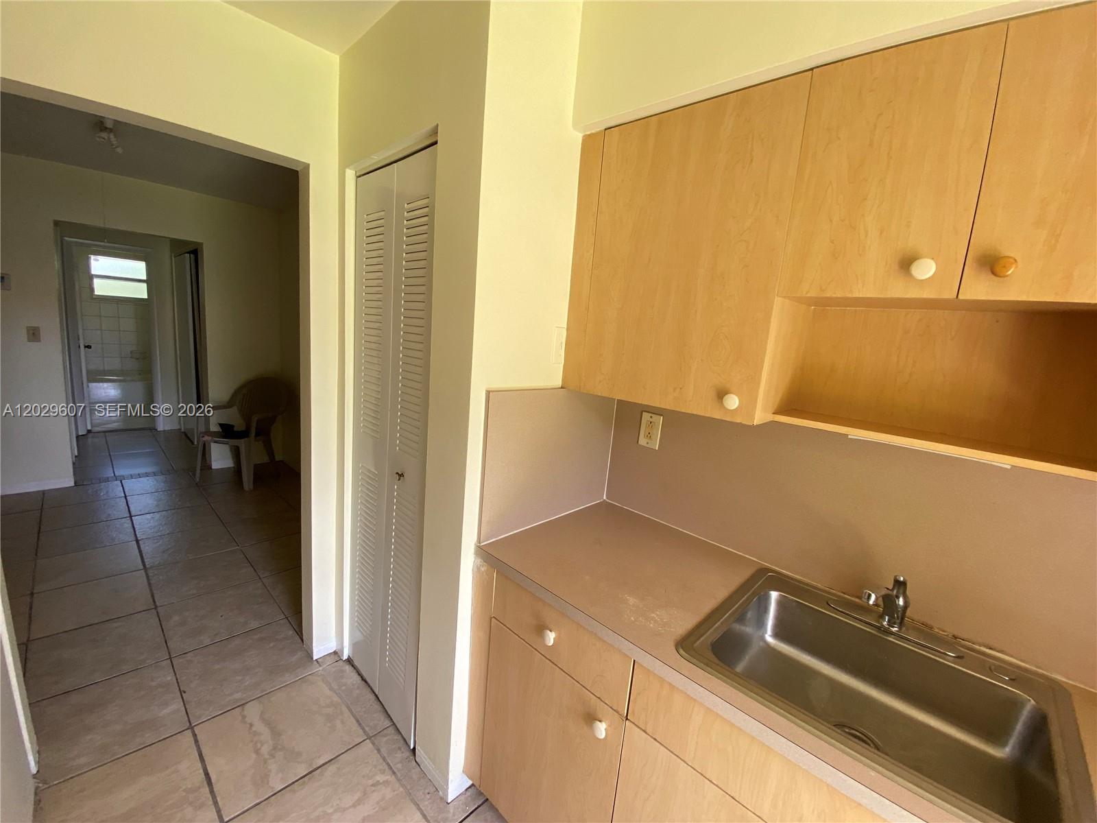 A kitchen area features light wood cabinets, a stainless steel sink, and tiled flooring — 2400 NE 188th St # 2404, Miami FL 33180, MIAMI, FL