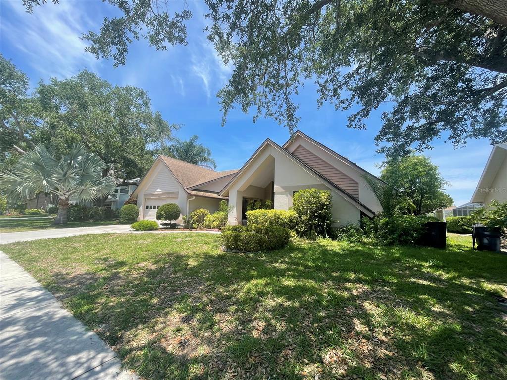 A single-story house with a tan exterior, a gabled roof, and a landscaped front yard — 4696 LONG LAKE DRIVE, SARASOTA, FL