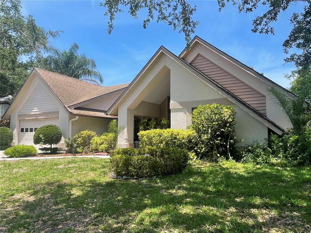 A single-story house with a peaked roof, beige stucco siding, and a two-car garage — 4696 LONG LAKE DRIVE, SARASOTA, FL