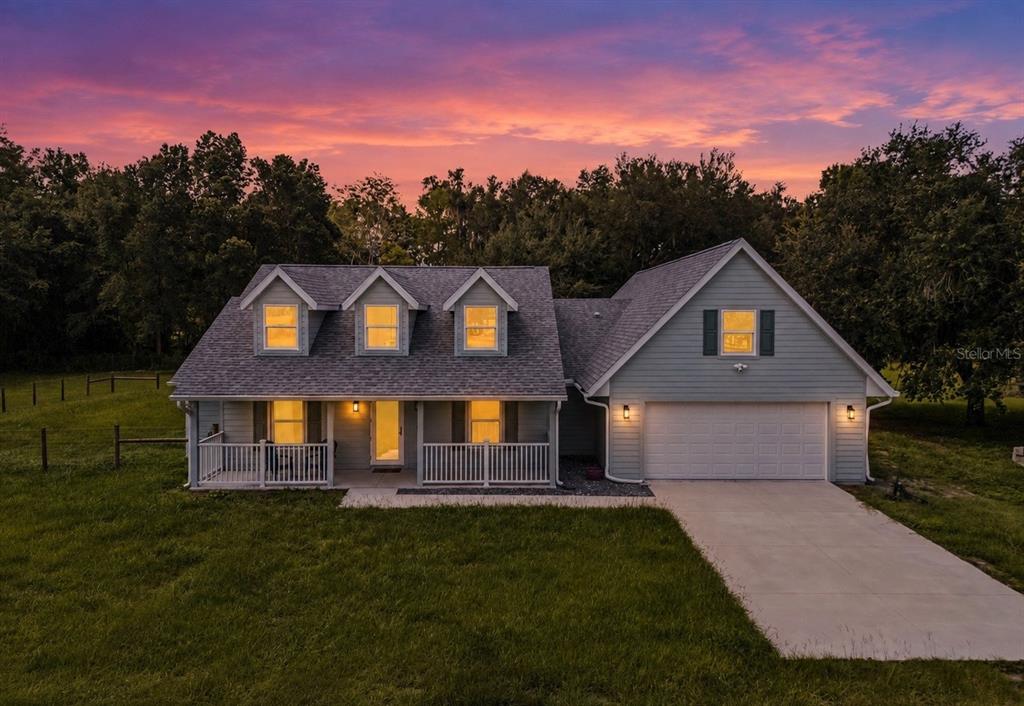 A light blue house with a front porch, three dormer windows, and an attached garage — 967 CR 753S, WEBSTER, FL