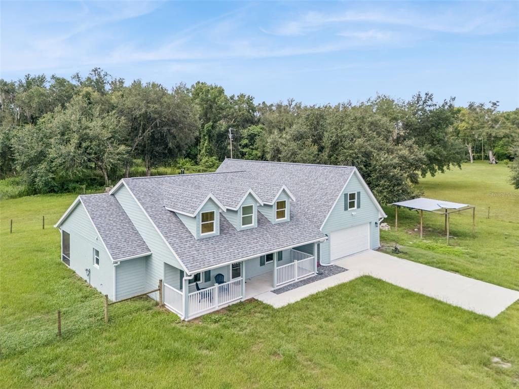 An aerial view of a light blue house with a white porch and three dormers — 967 CR 753S, WEBSTER, FL