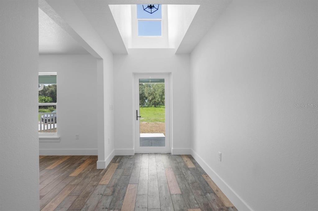 A bright room with wood-look flooring, a skylight, and a glass door leading outside — 967 CR 753S, WEBSTER, FL