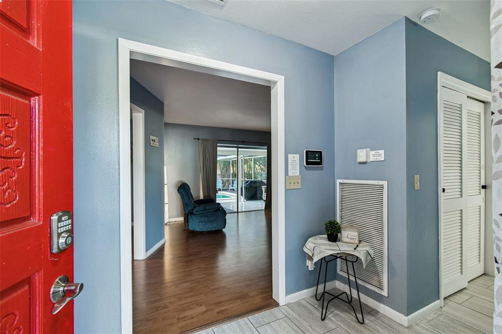 An entryway with a red door leads into a living area with wood-look flooring — 5005 PURITAN ROAD, TAMPA, FL