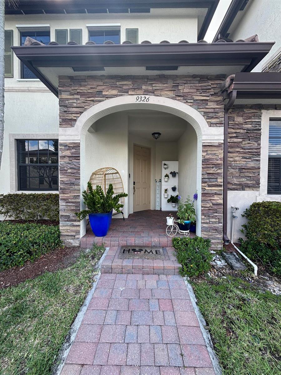 The exterior of a house features a stone-faced arched entryway with a brick walkway — 9326 W 33rd Lane, Hialeah FL 33018, HIALEAH, FL