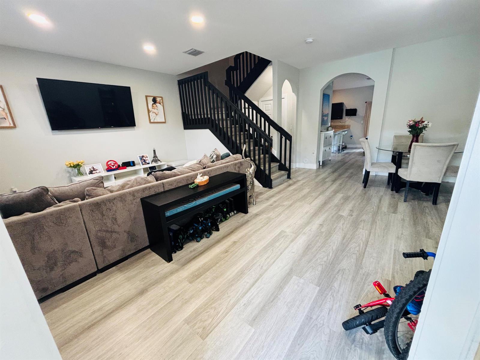 A living room with light wood floors, a sectional sofa, and a black staircase — 9326 W 33rd Lane, Hialeah FL 33018, HIALEAH, FL