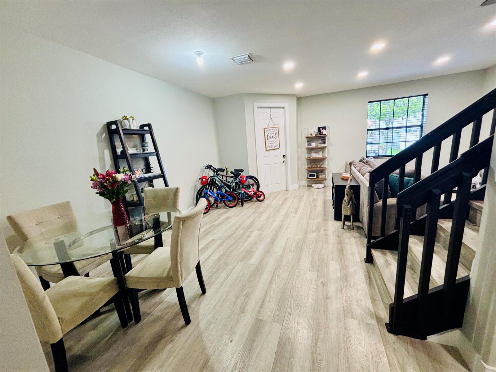 A dining area with a glass table and chairs sits next to a living room staircase — 9326 W 33rd Lane, Hialeah FL 33018, HIALEAH, FL