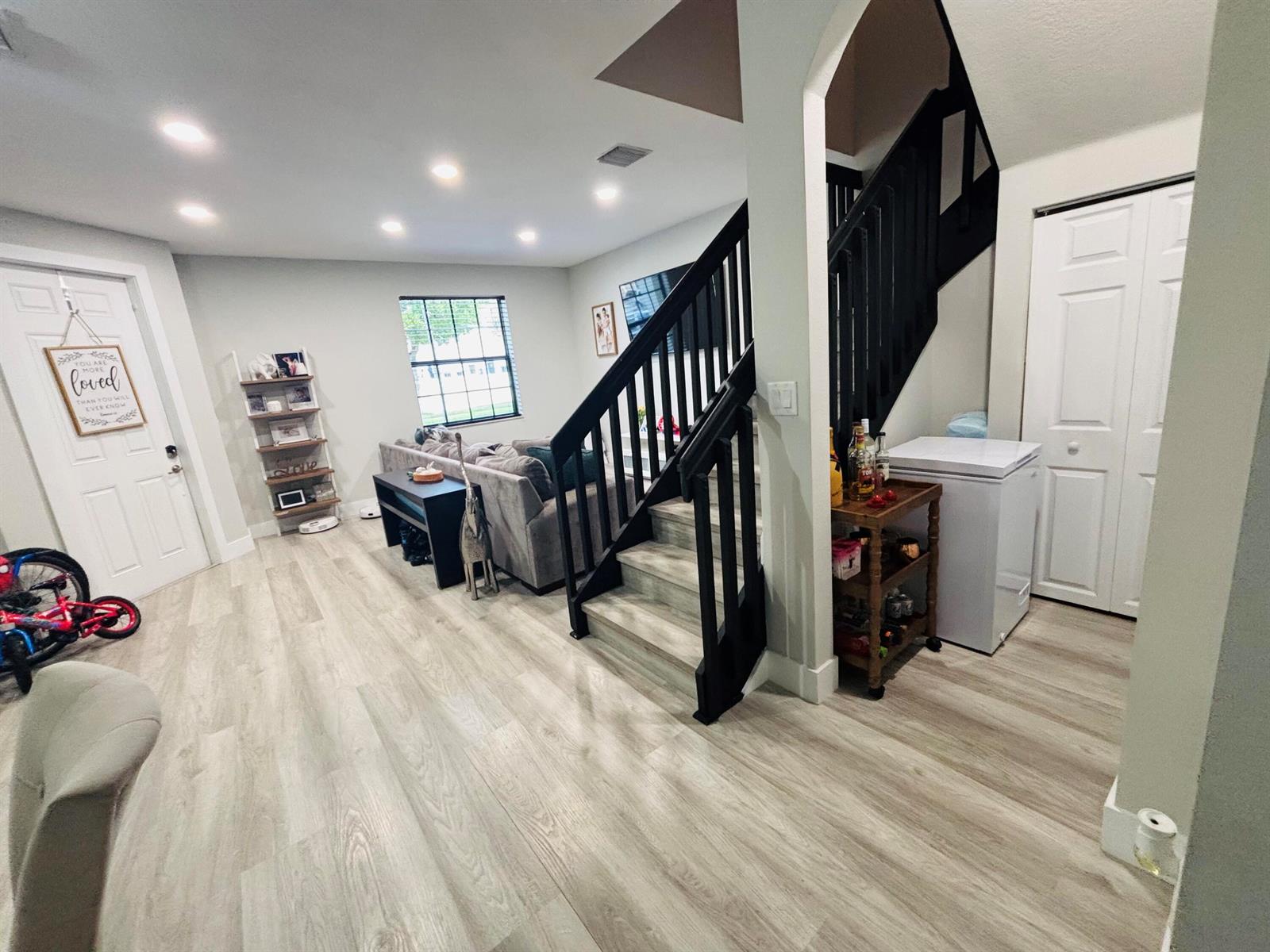 A living room features light wood-look flooring, a black staircase, and a white chest freezer — 9326 W 33rd Lane, Hialeah FL 33018, HIALEAH, FL