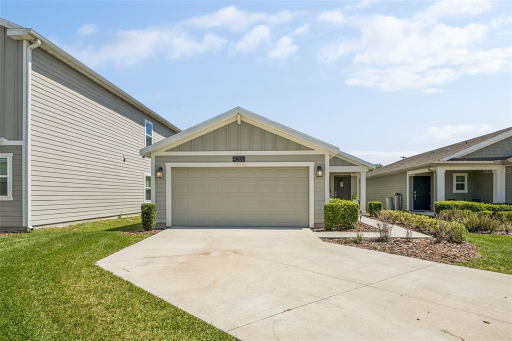 A single-story house with a beige garage and light-colored siding under a blue sky — 4366 SUNNY CREEK PLACE, KISSIMMEE, FL