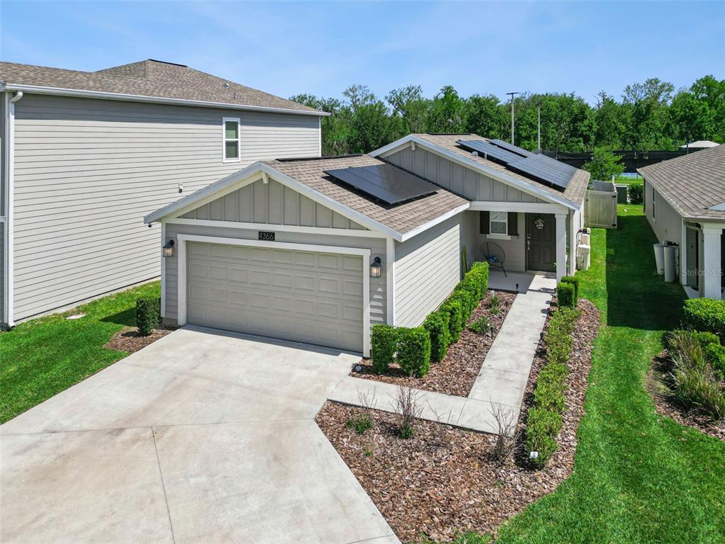 An exterior view of a single-story house with a garage and solar panels on the roof — 4366 SUNNY CREEK PLACE, KISSIMMEE, FL