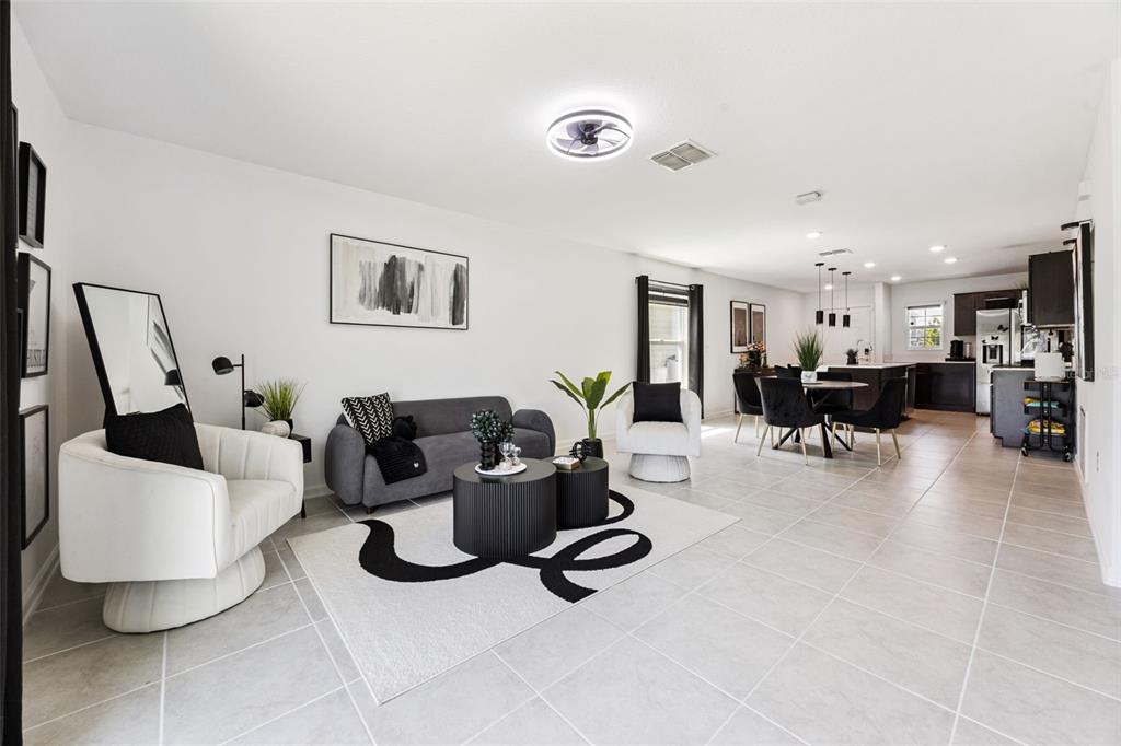 An open-concept living and dining area features tile flooring, modern furniture, and a neutral palette — 4366 SUNNY CREEK PLACE, KISSIMMEE, FL