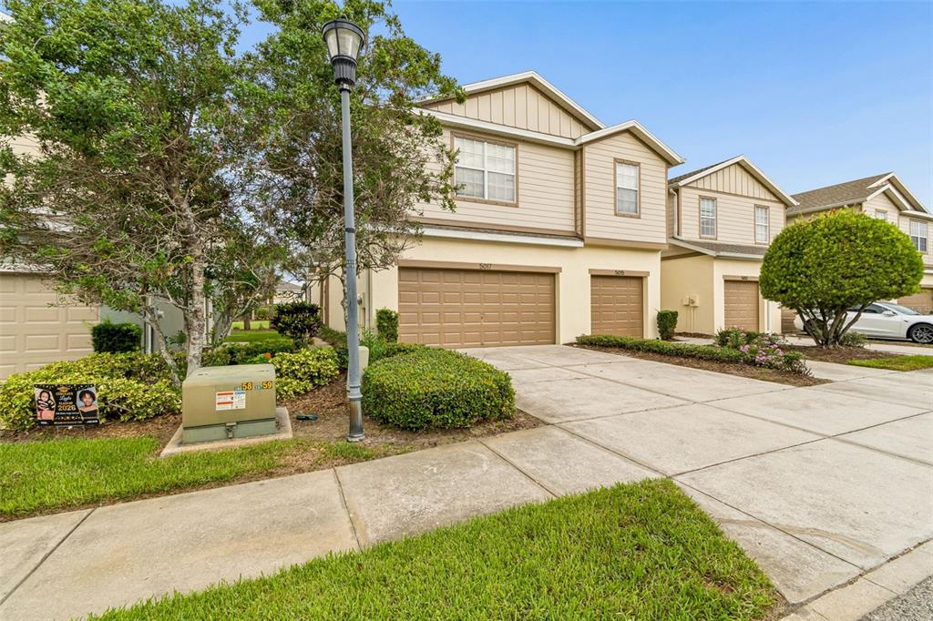 A beige two-story townhouse with a double garage and a small front yard — 5017 WHITE SANDERLING COURT, TAMPA, FL