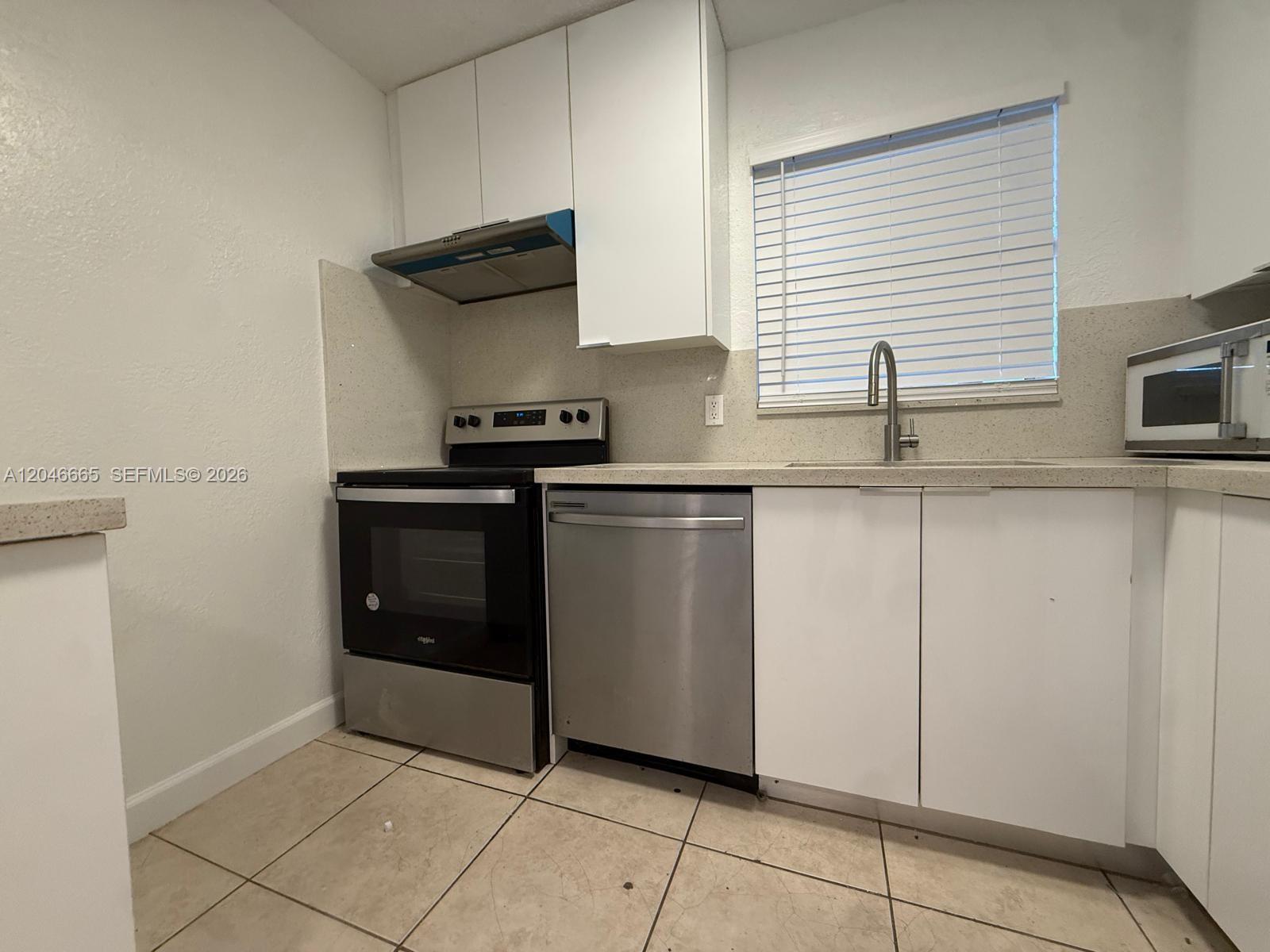 A kitchen features white cabinets, stainless steel appliances, a tiled floor, and a window — 400 NW 65th Ave # 202, Margate FL 33063, MARGATE, FL