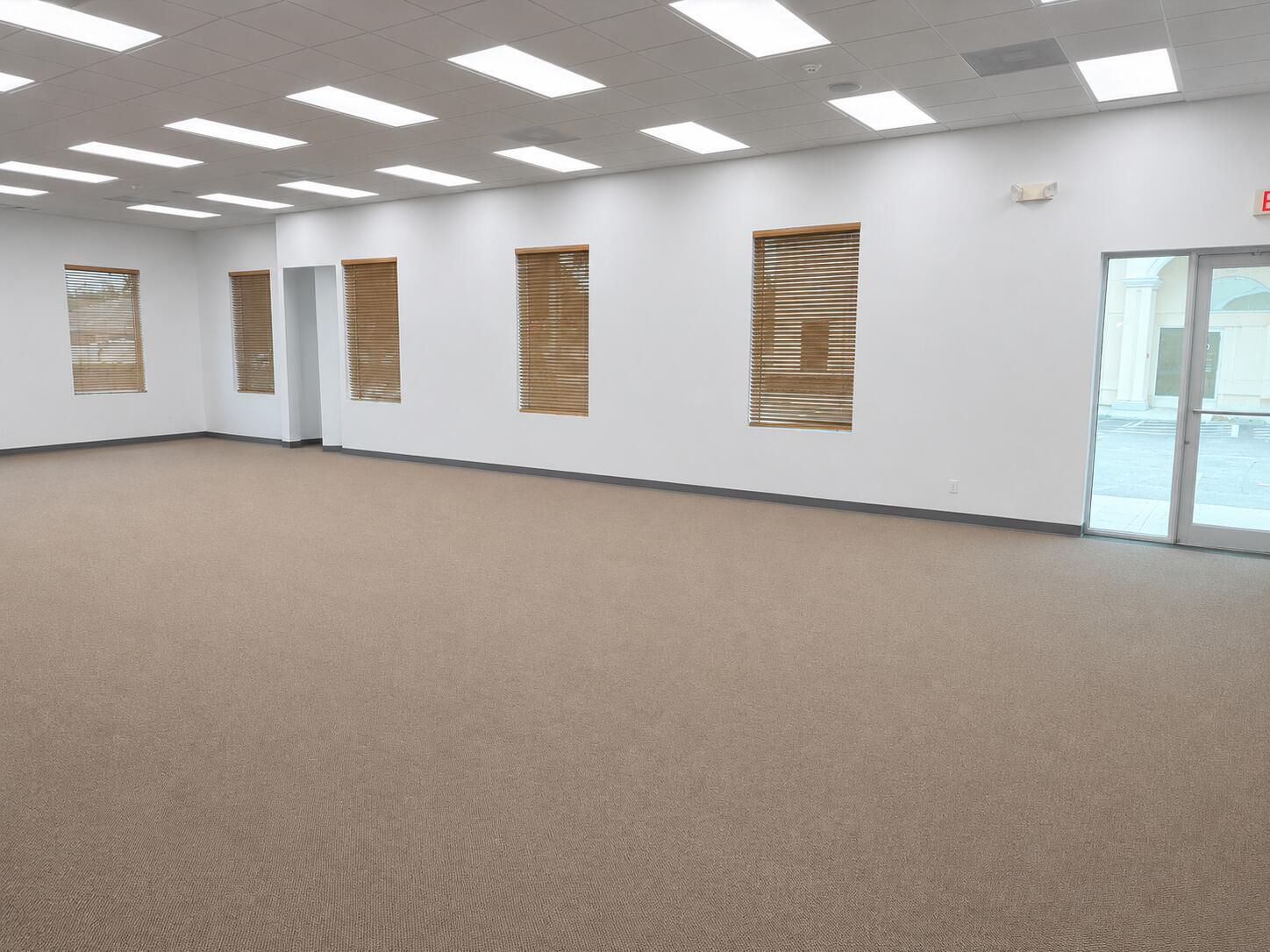 An empty office space with beige carpeting, white walls, multiple windows with blinds, and recessed lighting — 5055 S Congress Avenue # 301, Atlantis FL 33461, ATLANTIS, FL